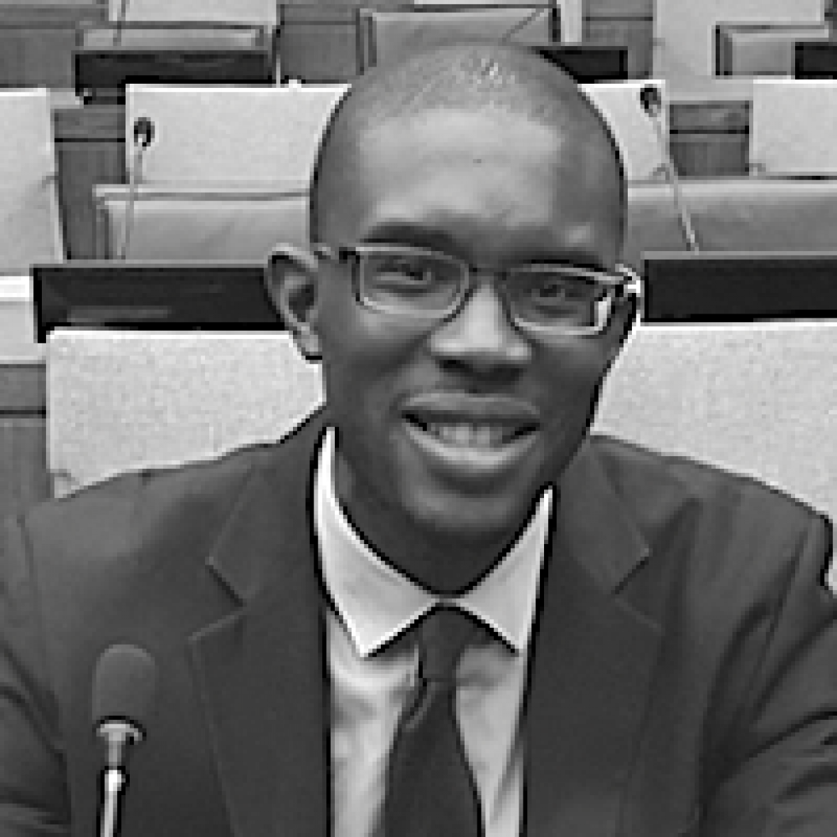 head and shoulders of Watson Fellow Lincoln Ajoku smiling at camera, wearing a suit and tie, in black and white