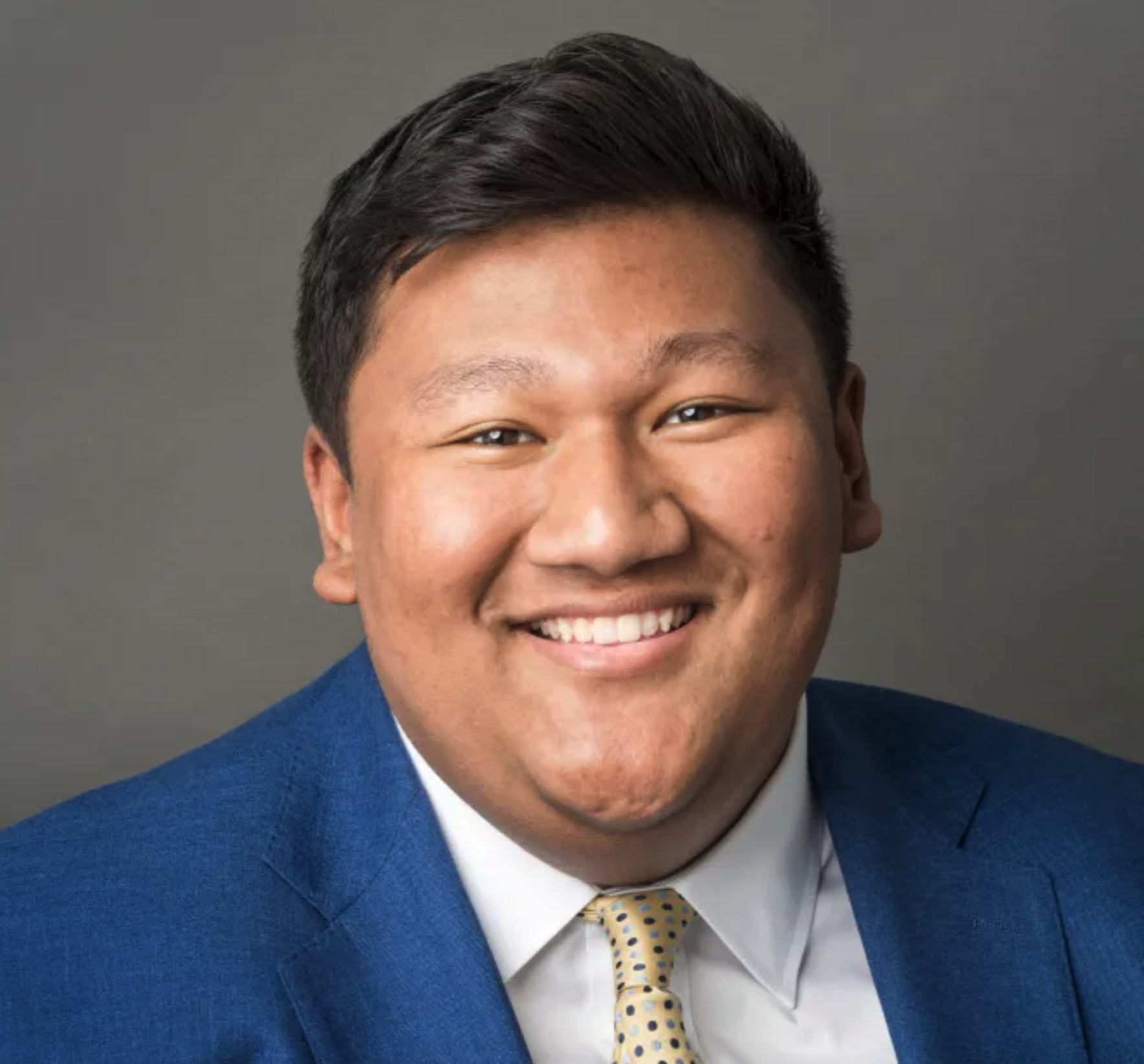 Headshot of Dave, young man wearing a sharp suit and sporting a winning smile